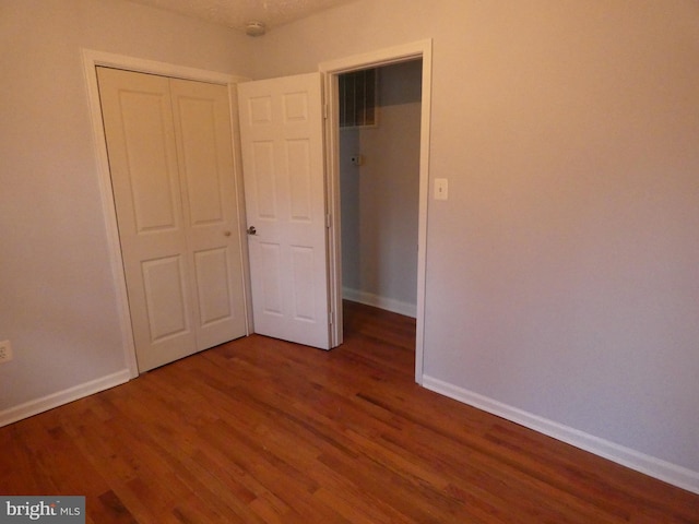 unfurnished bedroom featuring dark hardwood / wood-style flooring and a closet