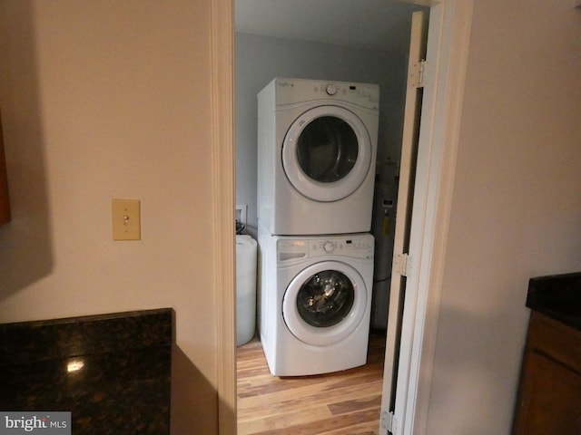 clothes washing area with stacked washing maching and dryer and light wood-type flooring