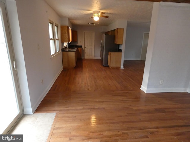 interior space featuring light wood-type flooring, stainless steel refrigerator, ceiling fan, and sink