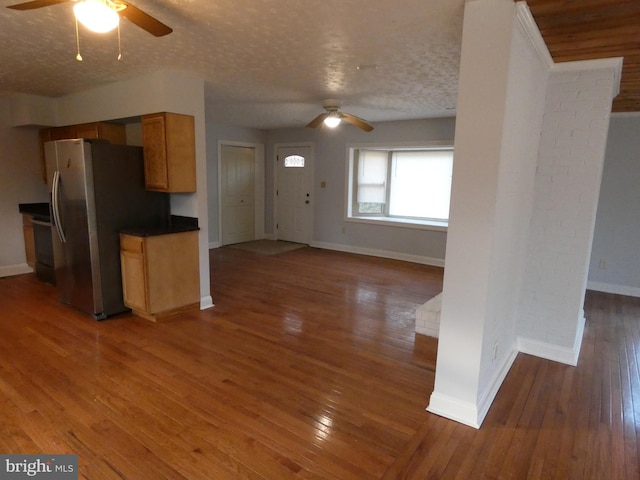 kitchen featuring stove, ceiling fan, stainless steel fridge, a textured ceiling, and dark hardwood / wood-style flooring