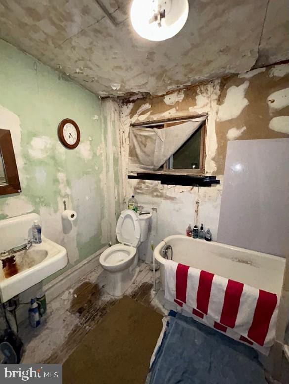 bathroom featuring a bathing tub, hardwood / wood-style floors, and toilet