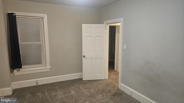 unfurnished bedroom featuring a closet and dark carpet