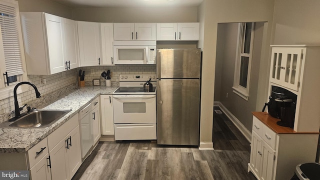 kitchen featuring white appliances, dark wood-type flooring, white cabinets, sink, and tasteful backsplash