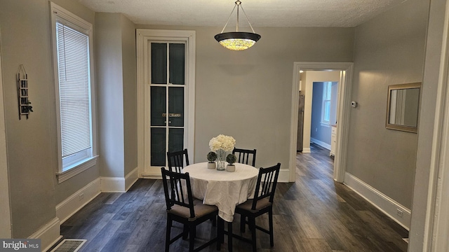 dining space with a textured ceiling, a wealth of natural light, and dark hardwood / wood-style floors