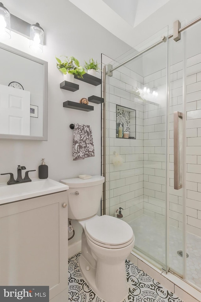 bathroom featuring tile patterned floors, vanity, an enclosed shower, and toilet