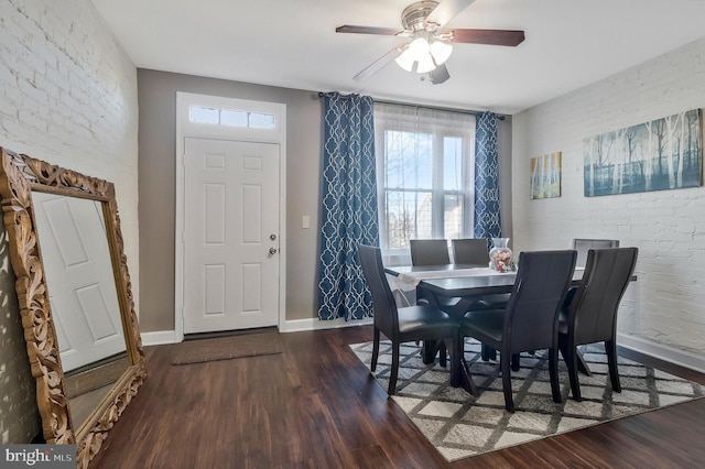 dining space featuring ceiling fan, brick wall, and dark hardwood / wood-style floors