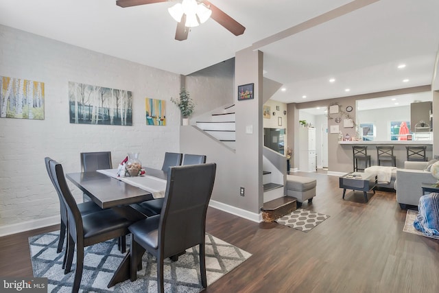 dining area with hardwood / wood-style flooring, ceiling fan, and brick wall