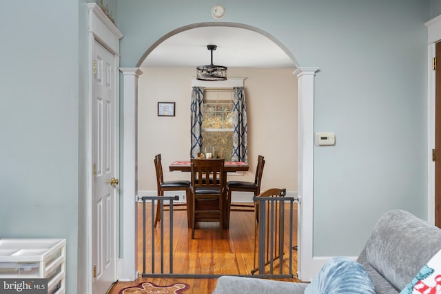 dining area featuring wood-type flooring and ornate columns