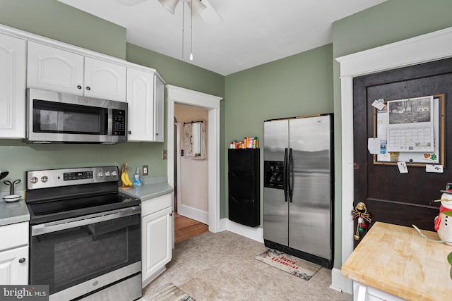 kitchen featuring light tile patterned floors, stainless steel appliances, white cabinetry, and ceiling fan