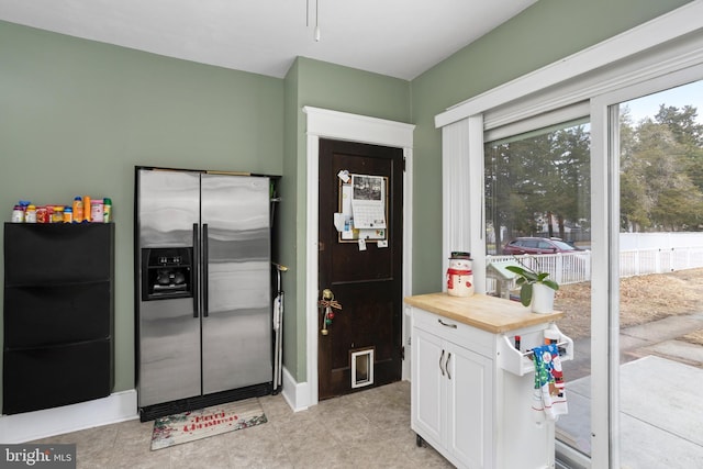 kitchen with white cabinets, butcher block counters, and stainless steel fridge with ice dispenser