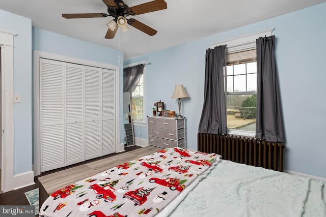 bedroom featuring hardwood / wood-style floors, a closet, radiator, and ceiling fan