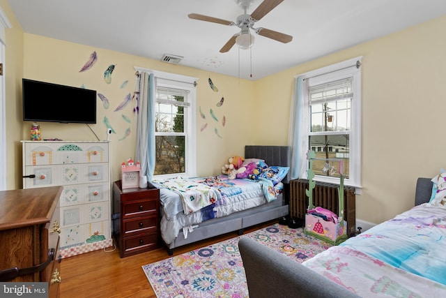 bedroom with hardwood / wood-style flooring, multiple windows, and ceiling fan