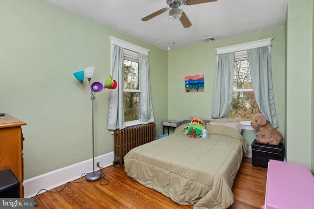 bedroom with ceiling fan, radiator heating unit, and light hardwood / wood-style flooring