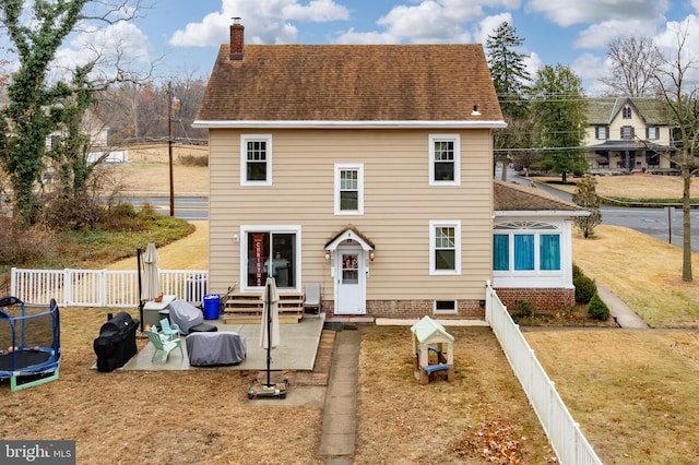 back of property with a yard, a patio, and a trampoline