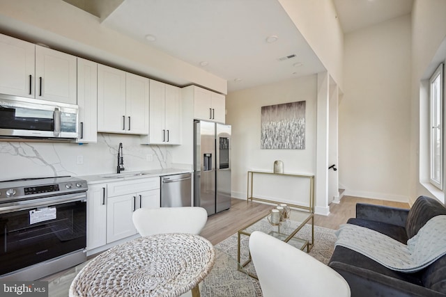 kitchen with a healthy amount of sunlight, sink, white cabinets, and stainless steel appliances