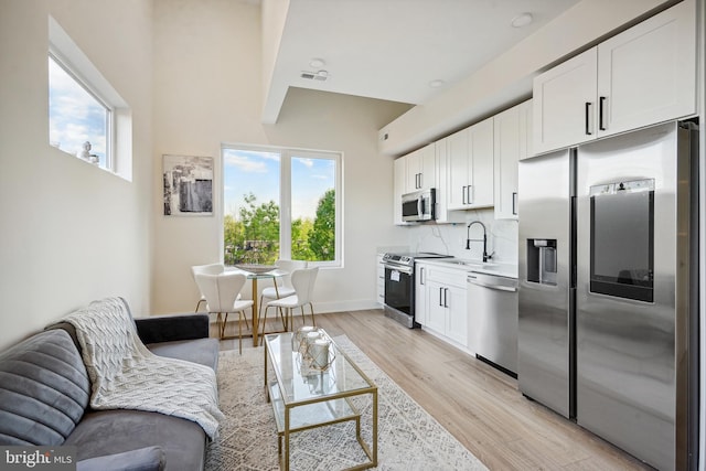 living room with sink, a healthy amount of sunlight, and light hardwood / wood-style floors