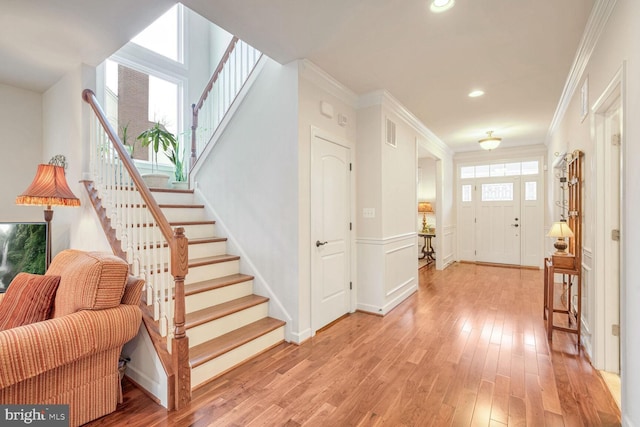 foyer entrance with crown molding and light hardwood / wood-style floors