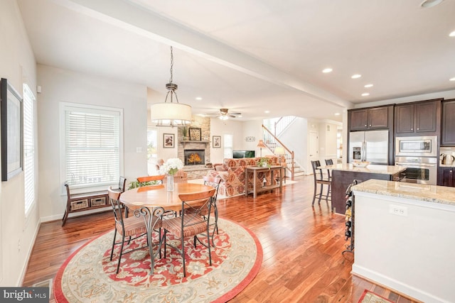 dining area featuring a stone fireplace and light wood-type flooring