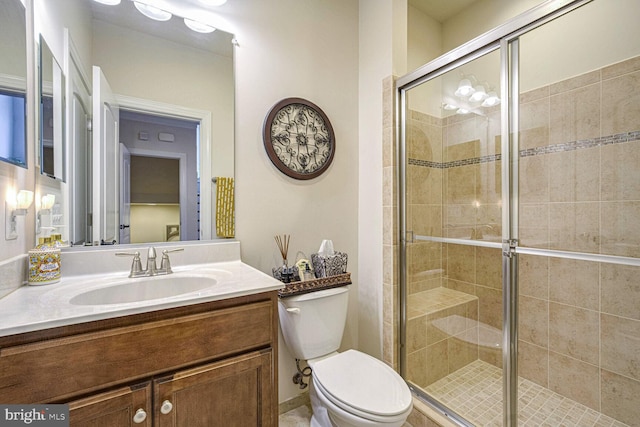 bathroom with vanity, a shower with shower door, and toilet