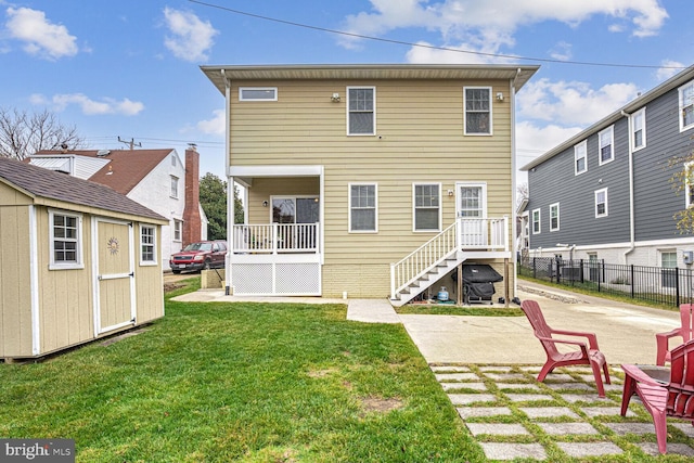 rear view of house with a lawn, a patio, and a storage unit