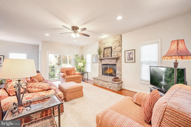 living room with a fireplace, light hardwood / wood-style flooring, and ceiling fan