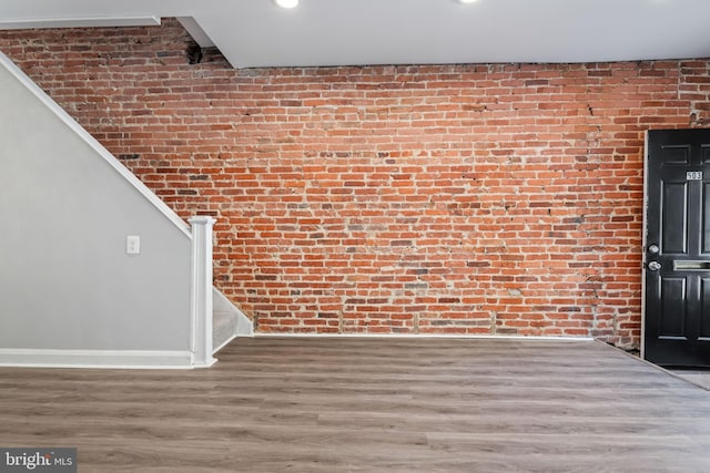 interior space featuring wood-type flooring and brick wall