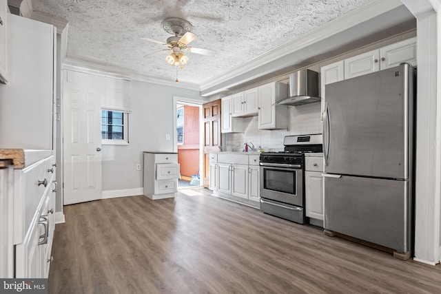 kitchen with hardwood / wood-style flooring, white cabinets, wall chimney range hood, and appliances with stainless steel finishes