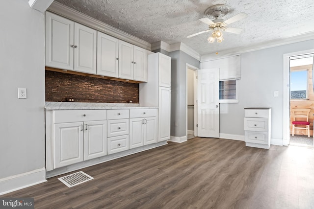 kitchen featuring dark hardwood / wood-style flooring, a textured ceiling, ceiling fan, crown molding, and white cabinets