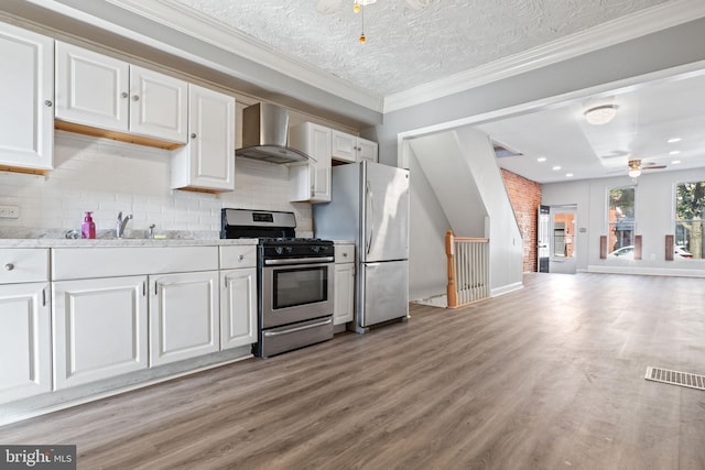 kitchen featuring white cabinets, wall chimney exhaust hood, light wood-type flooring, a textured ceiling, and stainless steel appliances