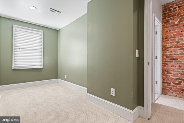 empty room featuring light carpet and brick wall