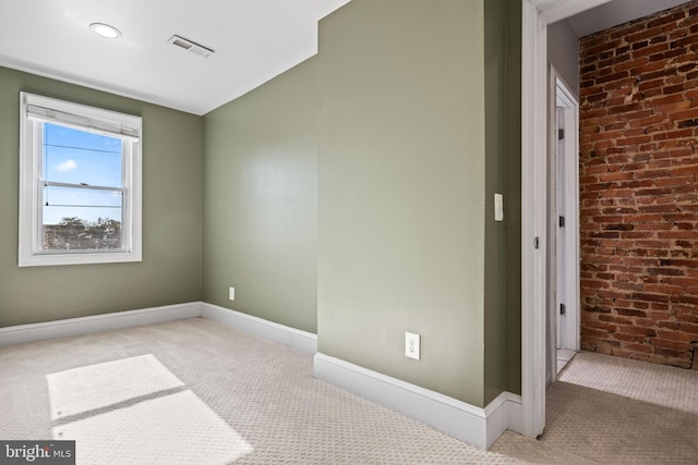 carpeted spare room with brick wall