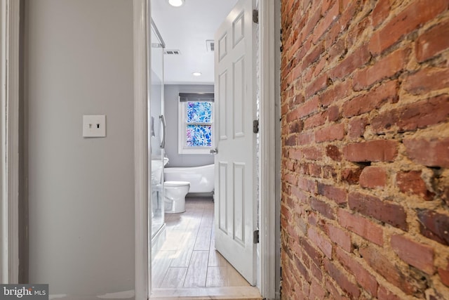 corridor with light hardwood / wood-style flooring and brick wall