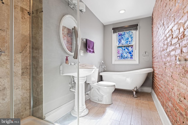 bathroom with hardwood / wood-style flooring, toilet, plus walk in shower, and brick wall