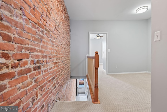 corridor with light colored carpet and brick wall