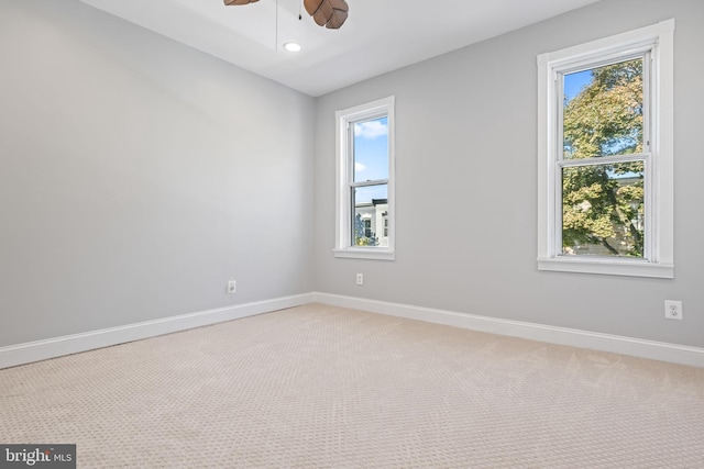 carpeted spare room featuring ceiling fan and a healthy amount of sunlight