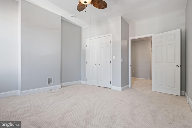 unfurnished bedroom featuring ceiling fan, a closet, and light colored carpet