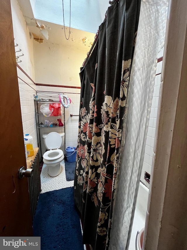 bathroom with tile patterned flooring, toilet, and tile walls