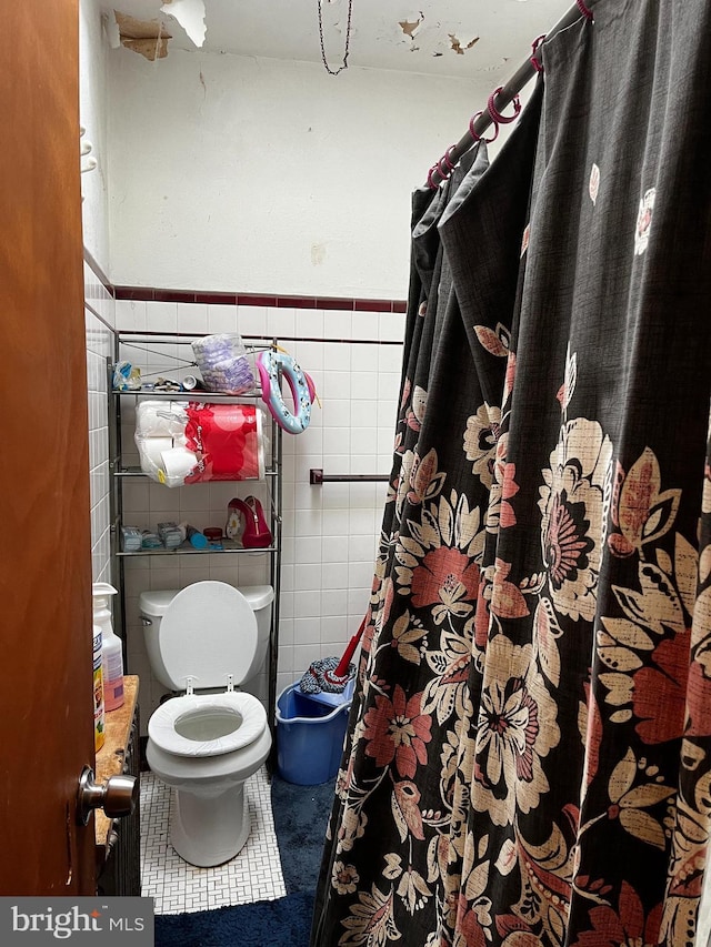 bathroom featuring tile patterned flooring, toilet, and tile walls