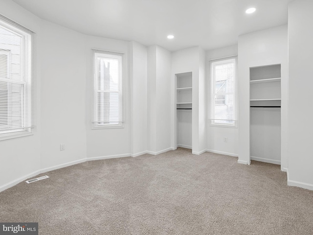 unfurnished bedroom with light colored carpet and multiple windows