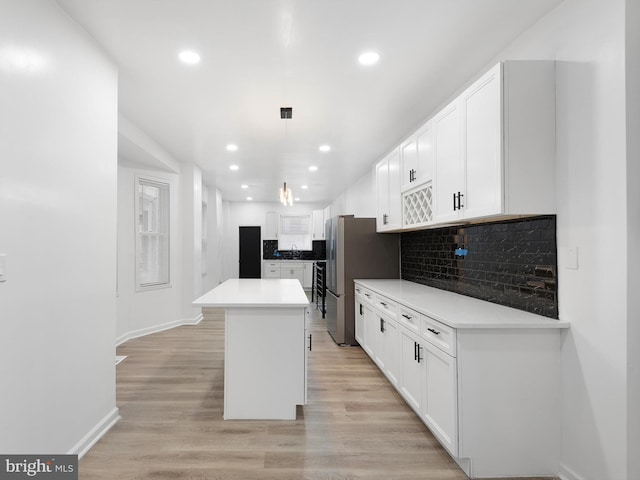 kitchen with decorative backsplash, pendant lighting, white cabinets, and a kitchen island