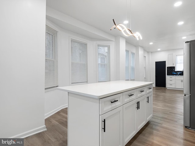 kitchen with decorative backsplash, a kitchen island, white cabinetry, and decorative light fixtures