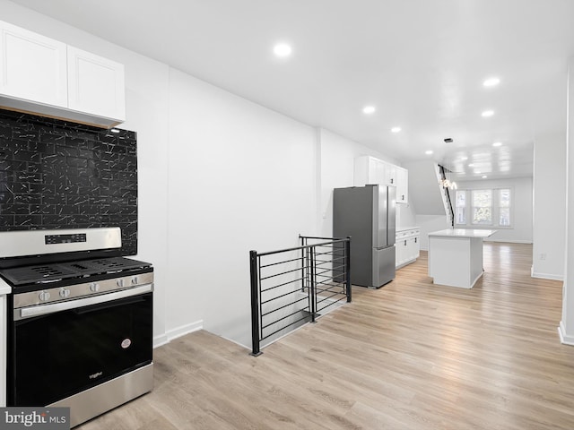 kitchen featuring decorative backsplash, stainless steel appliances, light hardwood / wood-style flooring, a notable chandelier, and white cabinets