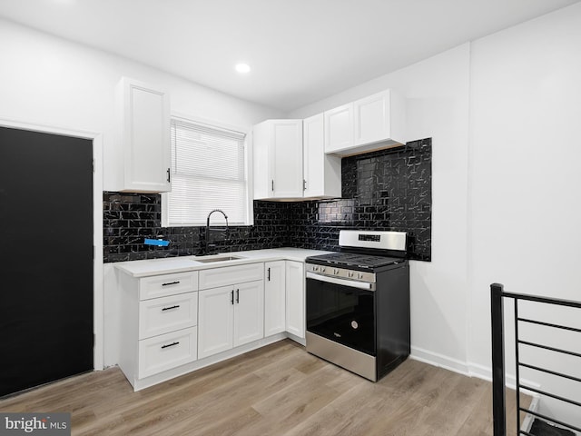 kitchen with sink, white cabinets, stainless steel range oven, and light wood-type flooring