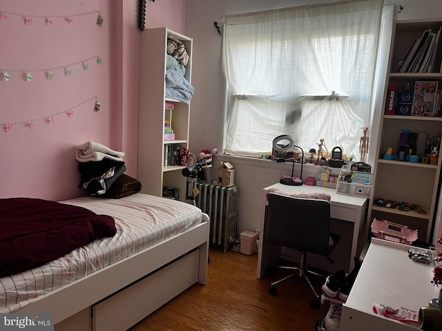 bedroom with wood-type flooring and radiator