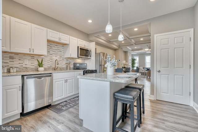 kitchen with coffered ceiling, stainless steel appliances, light hardwood / wood-style flooring, white cabinets, and a kitchen island