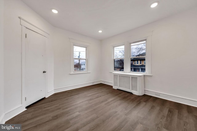 spare room featuring dark hardwood / wood-style floors and radiator