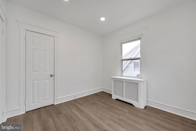 unfurnished room featuring radiator heating unit and wood-type flooring