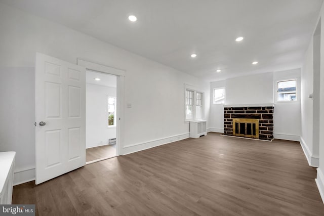 unfurnished living room featuring dark hardwood / wood-style flooring, baseboard heating, and radiator