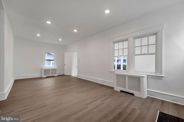 unfurnished room with hardwood / wood-style flooring, radiator, and a healthy amount of sunlight