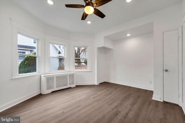 additional living space with ceiling fan, a healthy amount of sunlight, wood-type flooring, and radiator